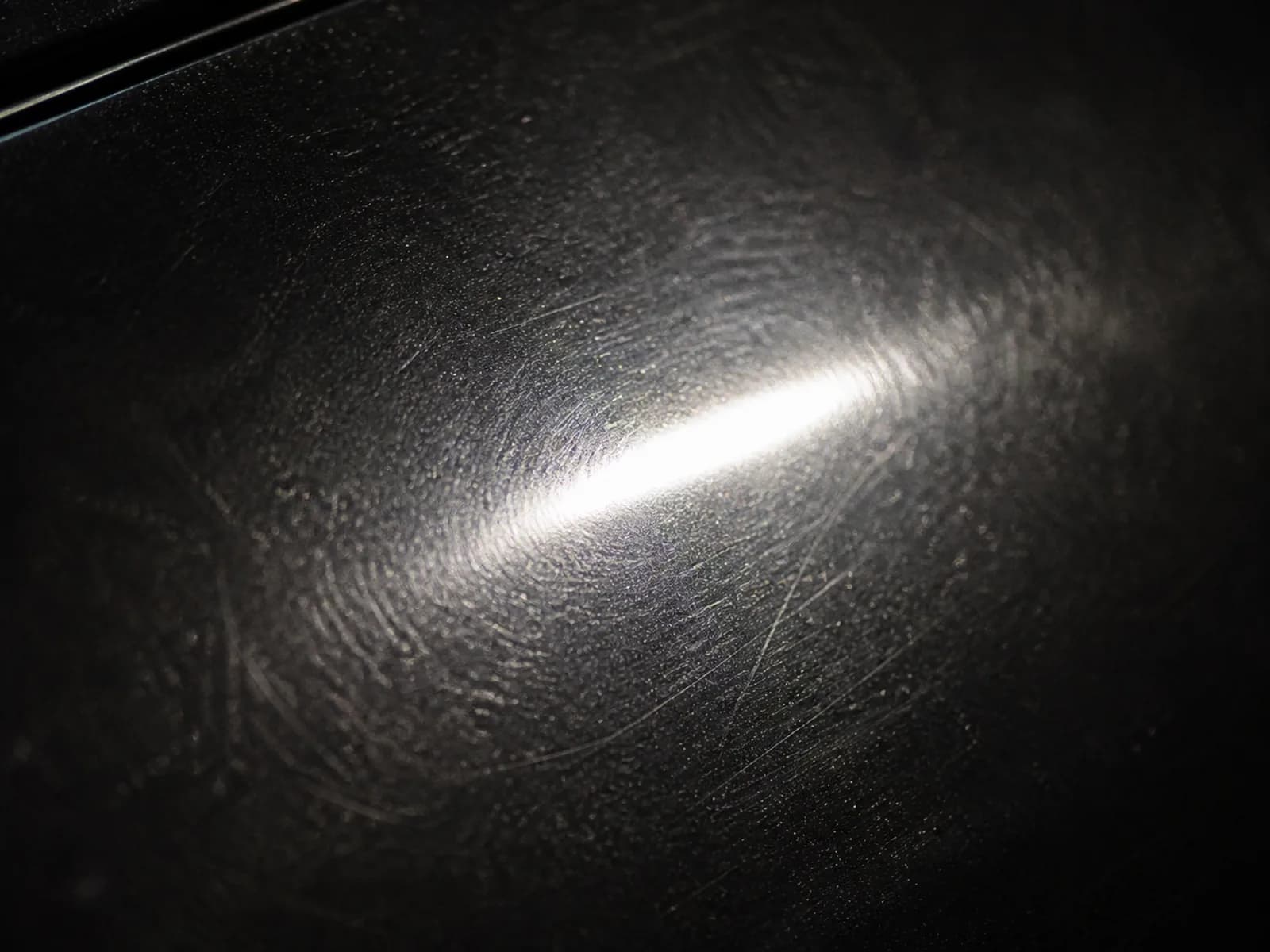 Schwarzer Autolack mit feinen Kratzern und matter Oberfläche